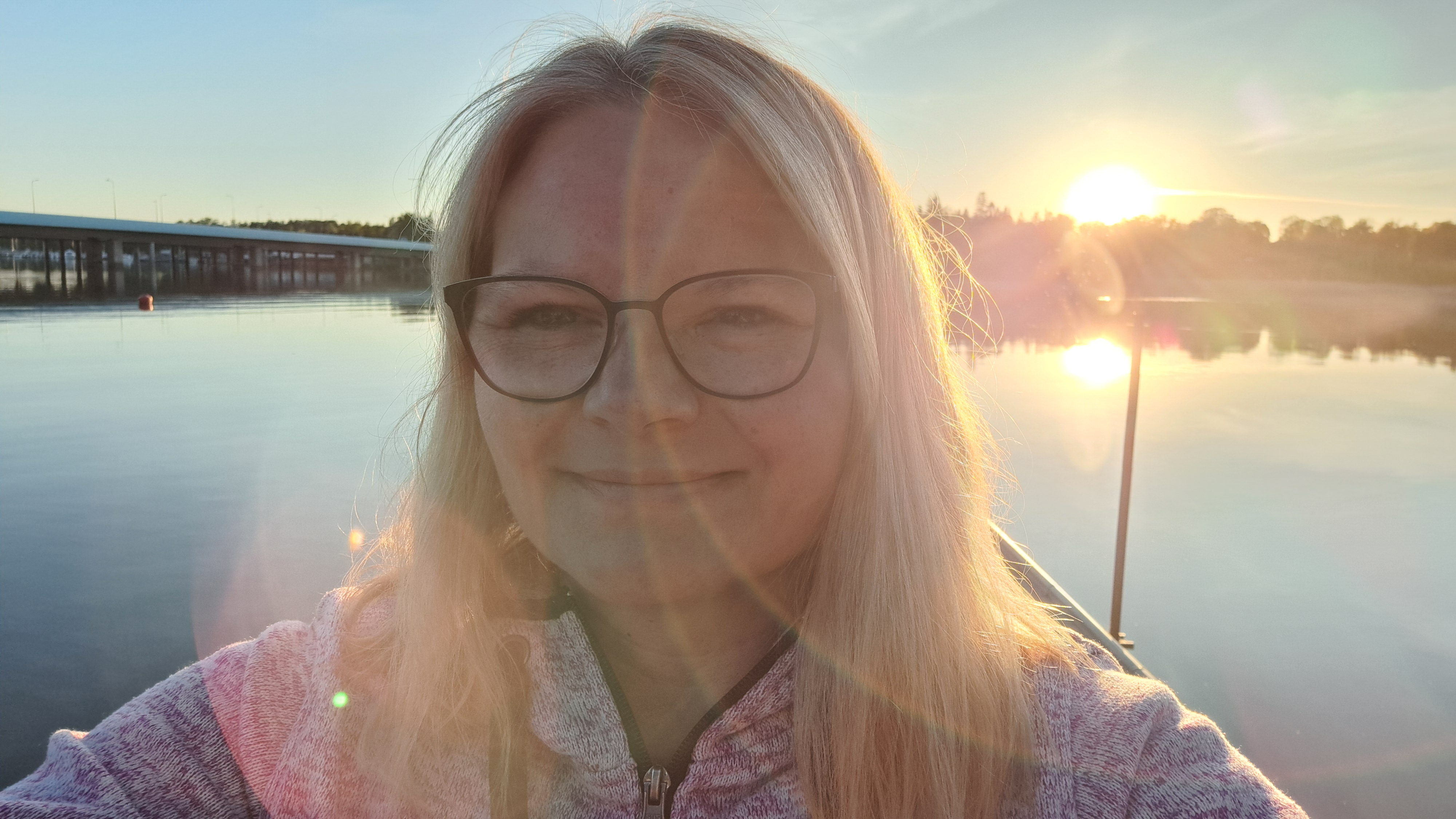 Tanja bei Sonnenaufgang am Wasser, mit einer Brücke im Hintergrund